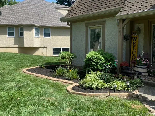 Foundation planting bed with stone edging and fresh mulch beside a home.