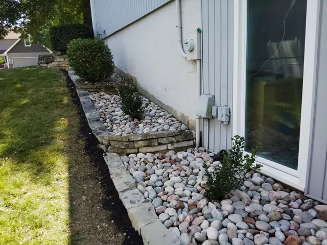 River-rock drainage strip with a stone border running along a home's foundation.